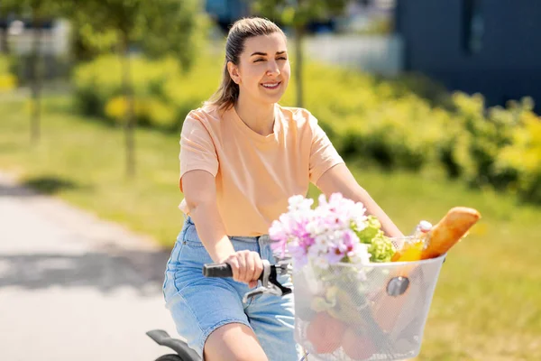 Donna con cibo e fiori nel cestino della bicicletta — Foto Stock