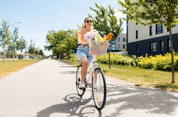 Kvinna med mat och blommor i cykelkorg — Stockfoto