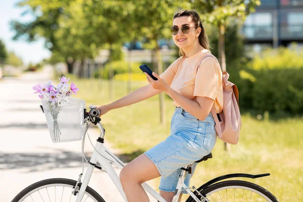 Kobieta ze smartfonem na rowerze w mieście — Zdjęcie stockowe