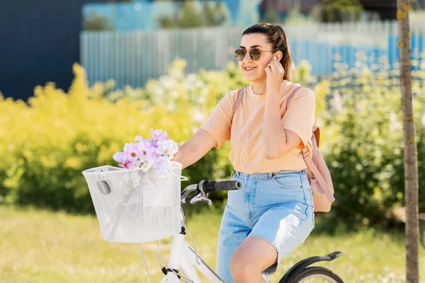 Femme heureuse avec écouteurs équitation vélo en ville — Photo