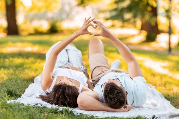 Casal feliz fazendo dedo coração no parque de verão — Fotografia de Stock