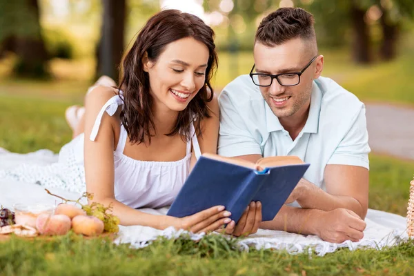 Un cuplu fericit citind o carte despre picnic în parcul de vară — Fotografie, imagine de stoc