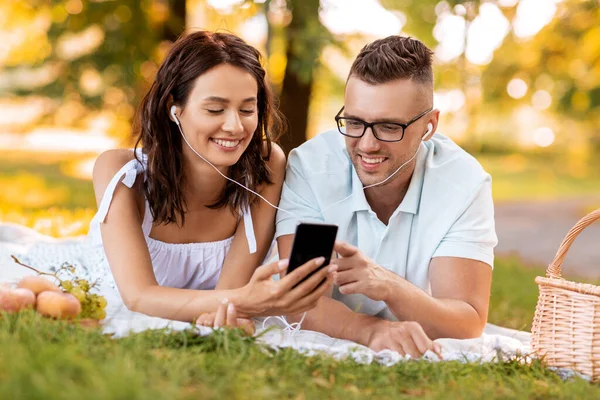 Couple with earphones and smartphone at picnic — Stock Photo, Image