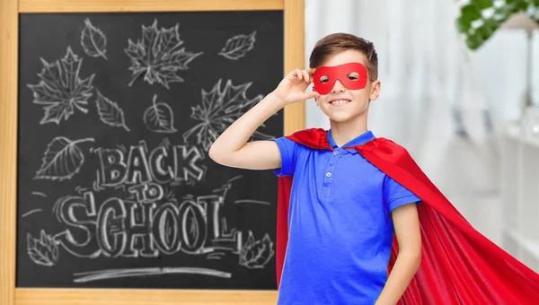 Garçon en costume de super héros sur tableau noir de l'école — Photo