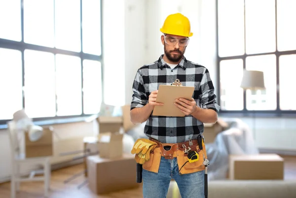 Construtor masculino no capacete com prancheta em casa — Fotografia de Stock