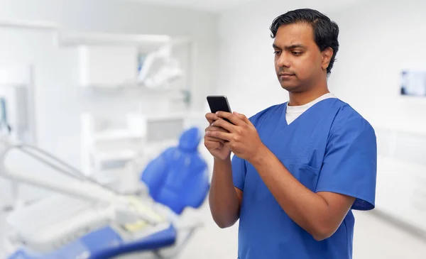 Médico indiano usando smartphone no consultório odontológico — Fotografia de Stock