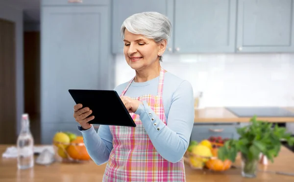 Smiling senior woman in apron with tablet computer — Stock Photo, Image