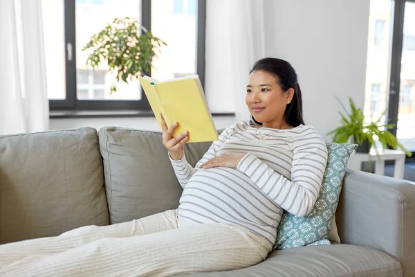 Boldog terhes nő olvasás könyv otthon — Stock Fotó