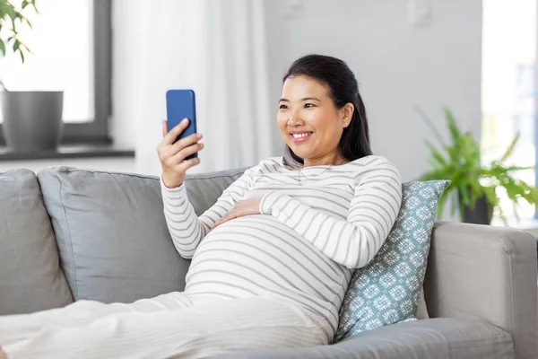 Gelukkig zwanger vrouw met smartphone thuis — Stockfoto