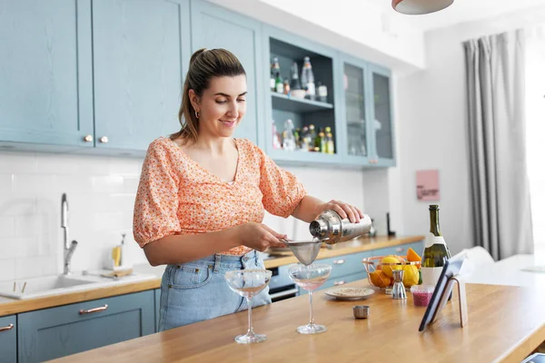 Жінка з планшетним ПК робить коктейлі на кухні — стокове фото