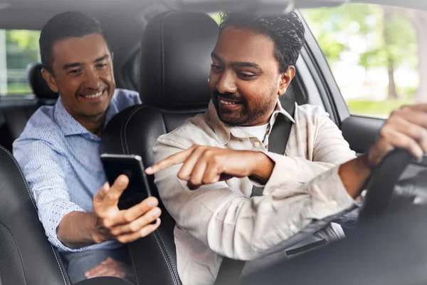 Passageiro masculino mostrando smartphone para motorista de carro — Fotografia de Stock