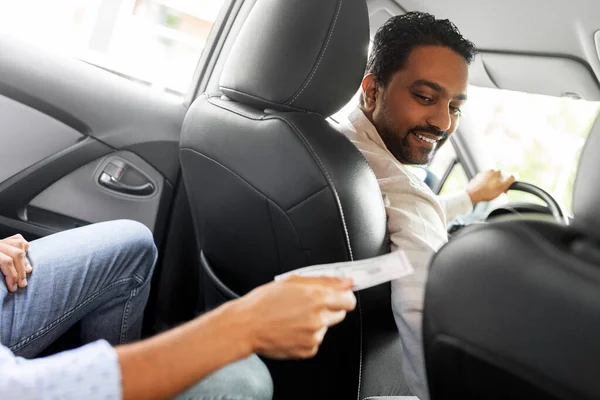 Пассажир дает деньги улыбающемуся водителю такси — стоковое фото