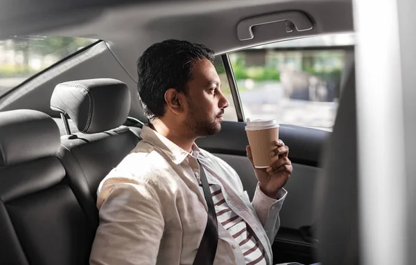 Homme indien avec café à emporter sur le siège arrière de la voiture — Photo