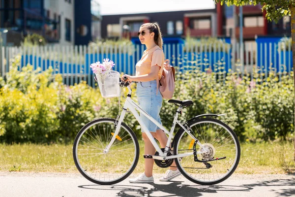 Donna con fiori nel cestino della bicicletta in città — Foto Stock