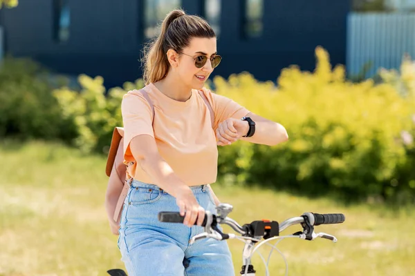 Donna con orologio intelligente in bicicletta in città — Foto Stock