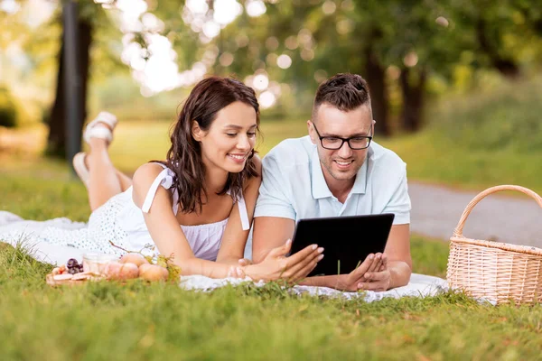 Gelukkig paar met tablet pc op picknick in park — Stockfoto