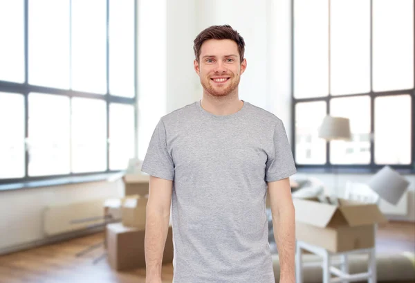 Jovem sorridente em camiseta cinza na nova casa — Fotografia de Stock