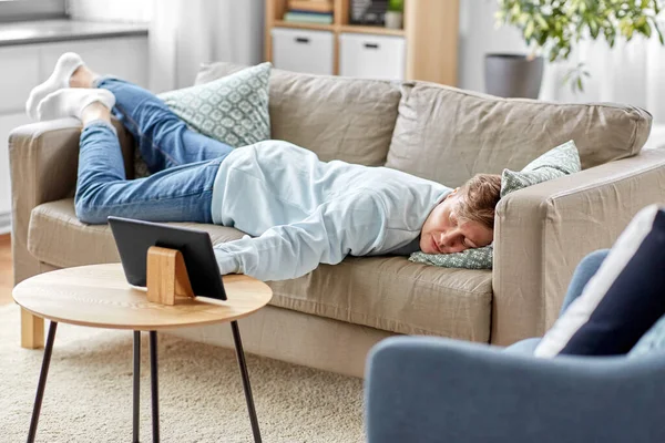 Homme ennuyé avec tablette PC couché sur le canapé à la maison — Photo