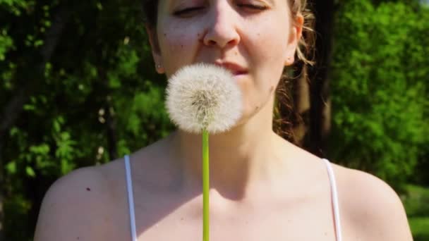 Kobieta dmuchanie nasiona mniszka lekarskiego w lecie — Wideo stockowe