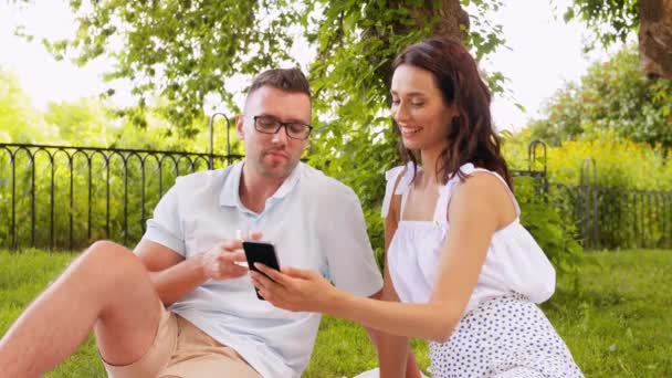 Casal feliz com smartphone no piquenique no parque — Vídeo de Stock