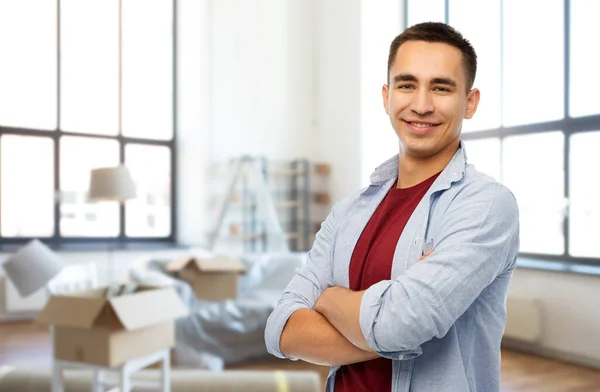 Glimlachende jonge man over nieuwe thuis achtergrond — Stockfoto