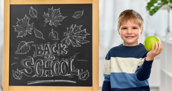 Little student boy with apple at school blackboard — Photo