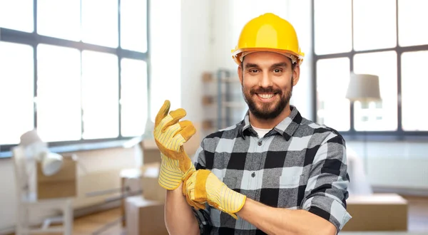 Glücklicher männlicher Baumeister mit Helm und Handschuhen zu Hause — Stockfoto