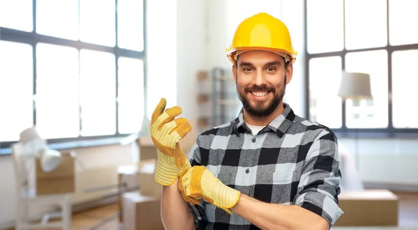 Feliz construtor masculino em capacete e luvas em casa — Fotografia de Stock