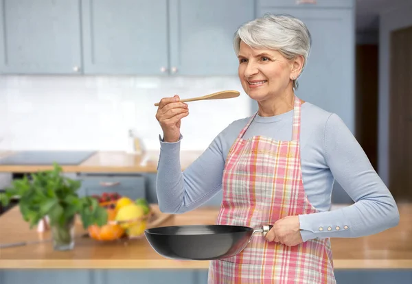 Donna anziana sorridente in grembiule con padella — Foto Stock