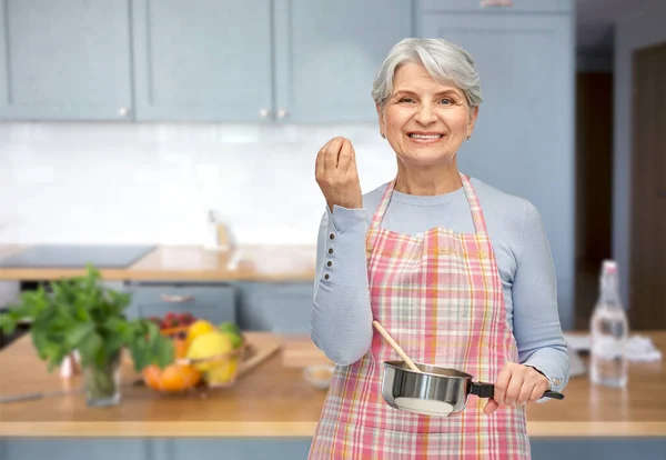 Donna anziana in grembiule con pentola cottura del cibo — Foto Stock