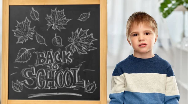 Bored little student boy over school blackboard Stockfoto