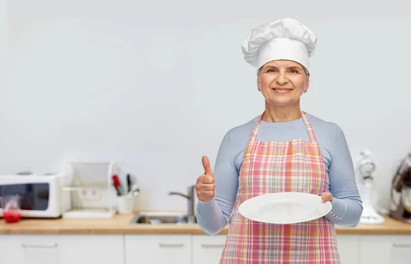Улыбающаяся пожилая женщина или шеф-повар с пустой тарелкой — стоковое фото