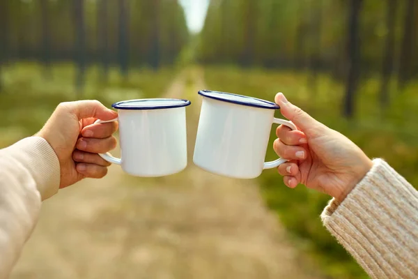 Couple clinking white tea mugs in forest — Stok fotoğraf