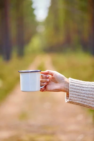Mano de mujer con taza de té blanco en el bosque — Foto de Stock
