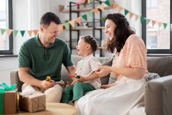 Gelukkig gezin met geschenken en party blowers thuis — Stockfoto