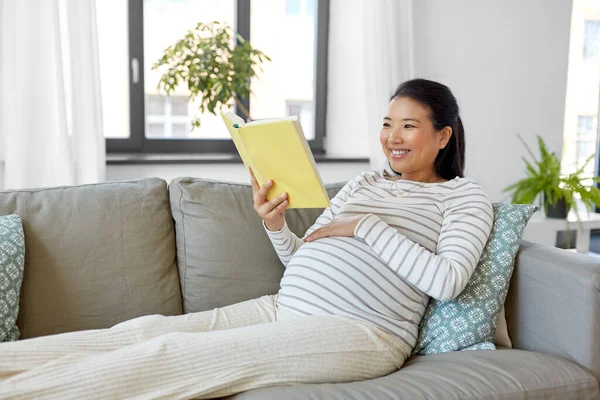 Heureuse femme enceinte lecture livre à la maison — Photo