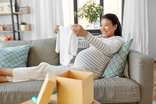 Mulher grávida feliz com babys bodysuit em casa — Fotografia de Stock