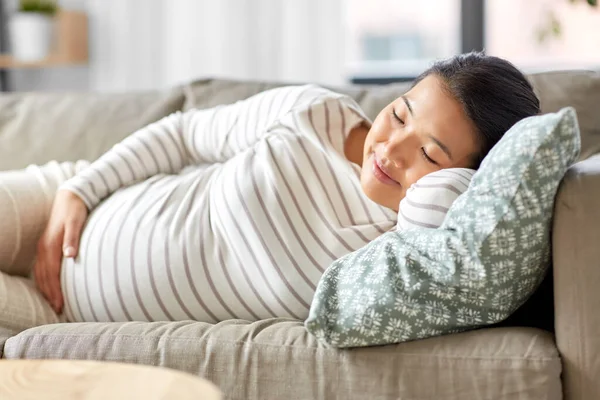 Беременная азиатка спит дома на диване — стоковое фото