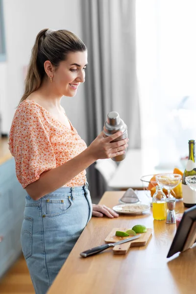 Woman with tablet pc making cocktails at kitchen — Stock Photo, Image