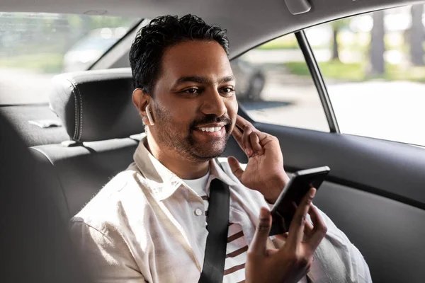 Пассажир с наушниками и сотовым телефоном в машине такси — стоковое фото