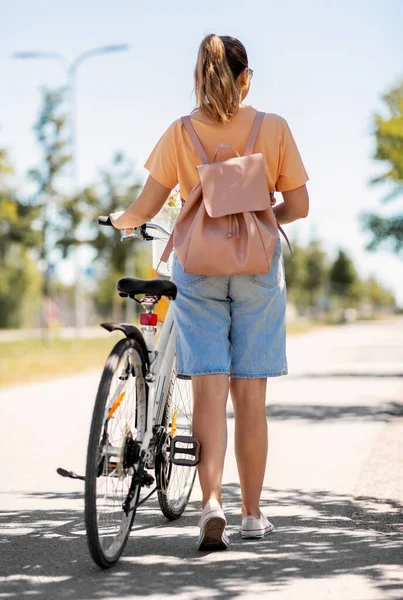 Vrouw met fiets en rugzak wandelen in de stad — Stockfoto