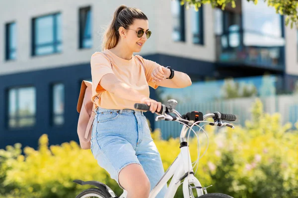 Vrouw met slim horloge paardrijden fiets in de stad — Stockfoto