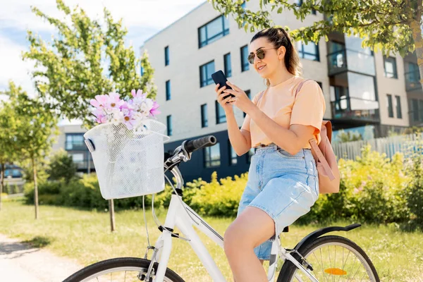 Donna con smartphone in bicicletta in città — Foto Stock