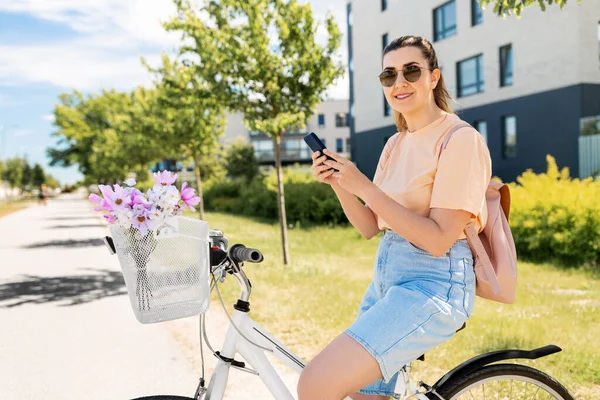 Kvinna med smartphone på cykel i staden — Stockfoto
