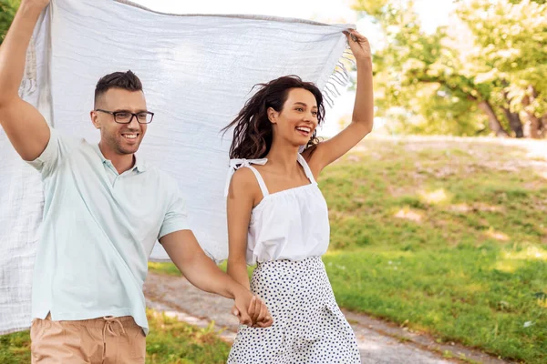 Счастливая пара с одеялом для пикника в летнем парке — стоковое фото