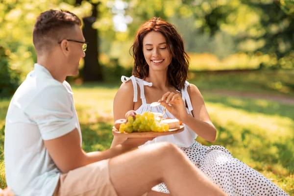 Casal feliz fazendo piquenique no parque de verão — Fotografia de Stock