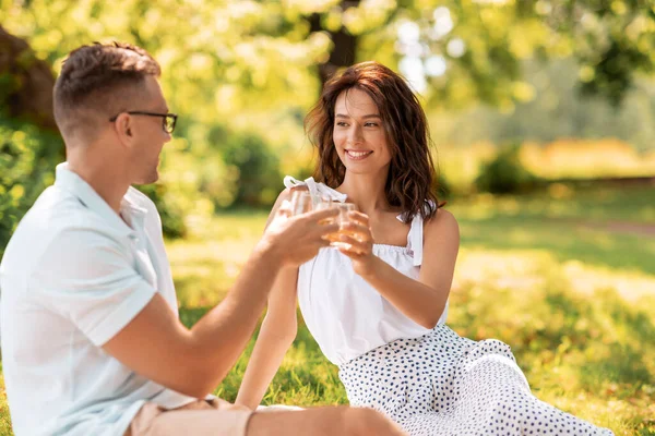 Feliz pareja brindis bebidas en el parque de verano —  Fotos de Stock