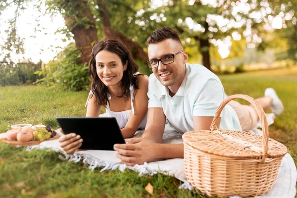 Casal feliz com tablet pc no piquenique no parque — Fotografia de Stock