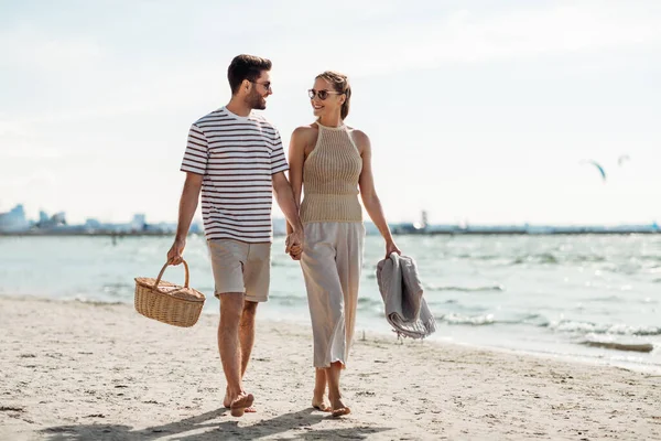 Lyckligt par med picknickkorg promenader på stranden — Stockfoto