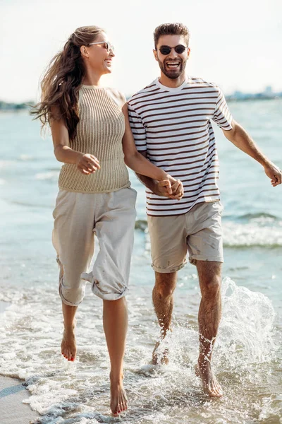 Счастливая пара бегает вдоль летнего пляжа — стоковое фото